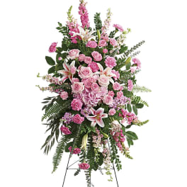Tall standing spray of pink roses, lilies, and carnations on a metal easel