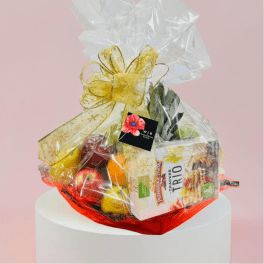 Gift basket with snacks and fruit wrapped in clear cellophane and a gold bow