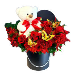 White teddy bear in red roses and a black hatbox