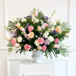 Large mixed flower arrangement in a white urn vase