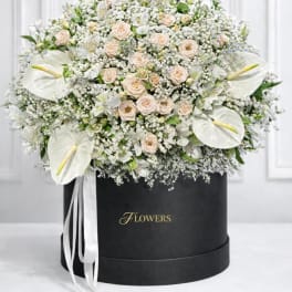 Large white floral arrangement with roses and calla lilies in a black hat box