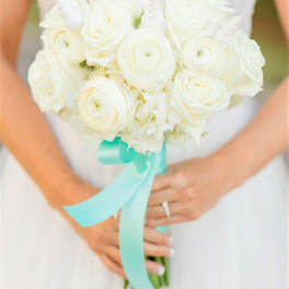 Bride holding a white rose bouquet with a turquoise ribbon