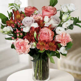 Mixed bouquet of pink, white, and orange flowers in a clear glass vase