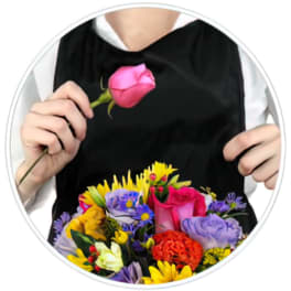 Person holding a pink rose above a colorful mixed bouquet