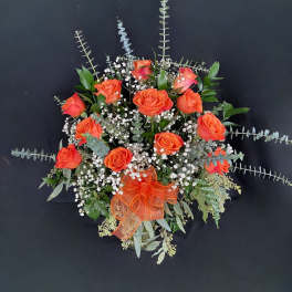 Orange roses in a glass vase with baby's breath and greenery