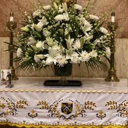 Large white floral altar arrangement with lilies and daisies in a vase