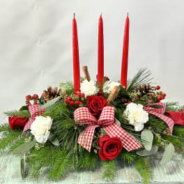 Holiday centerpiece with red candles, roses, and white carnations