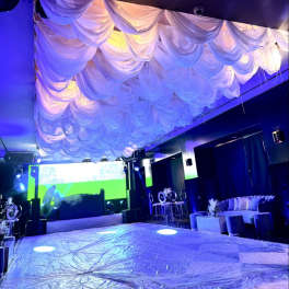 Event venue with draped white ceiling fabric and blue lighting