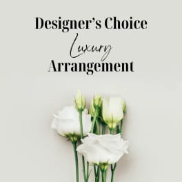 White roses with green buds beneath "Designer’s Choice Luxury Arrangement" text