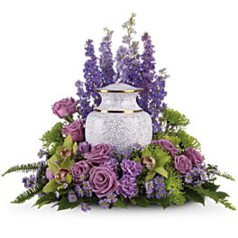 Purple floral arrangement around a white urn vase