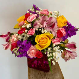Mixed bouquet with yellow roses, pink and purple flowers in a magenta vase