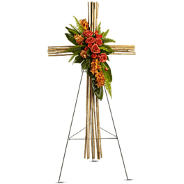 Floral cross on an easel with orange roses and greenery