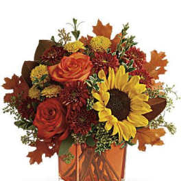 Autumn bouquet with roses, sunflower, and mums in an orange glass vase