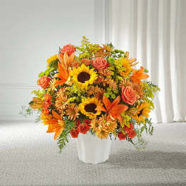 Orange and yellow mixed flower arrangement in a white vase