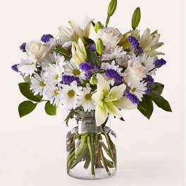 White lilies, roses, and daisies in a glass vase