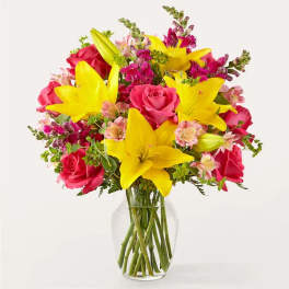 Bouquet of pink roses and yellow lilies in a clear glass vase