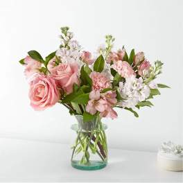 Pink roses and mixed pink-white flowers in a clear glass vase