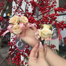 Two cream rose boutonnieres with pink ribbon accents