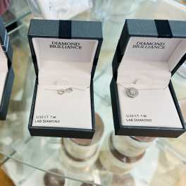 Three open jewelry boxes with necklaces on a glass table
