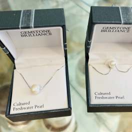 Two pearl necklaces in open jewelry boxes