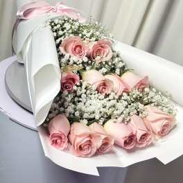 Pink roses with baby's breath in white wrapping and a pink ribbon