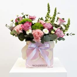 Pink roses and carnations in a pastel gift box with a lavender ribbon