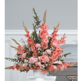 Tall pink floral arrangement in a white vase with a satin ribbon