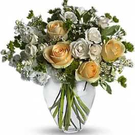 Bouquet of cream and pale yellow roses in a clear glass vase
