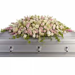 Pastel rose and white floral casket spray on a silver casket