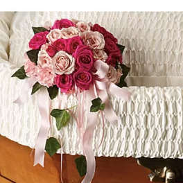 Pink and white rose bouquet with trailing ribbon on a casket