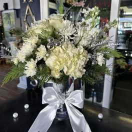 White floral arrangement in a silver vase with a satin bow