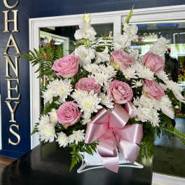 Pink roses and white daisies in a white basket with a pink ribbon
