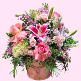 Pink and white floral arrangement in a round box with lilies and roses