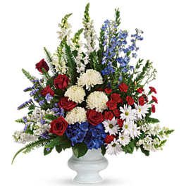 Large red, white, and blue floral arrangement in a white vase