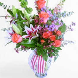 Mixed bouquet of pink roses and lilies in a striped glass vase
