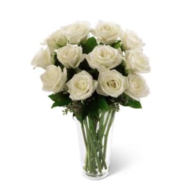 Tall clear vase filled with long-stemmed white roses.