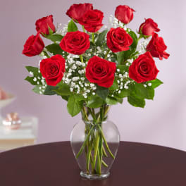 Red roses arranged in a clear glass vase with white baby's breath