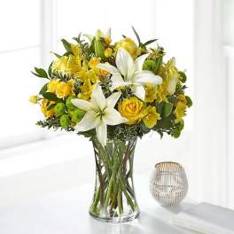 Yellow roses and white lilies in a clear glass vase