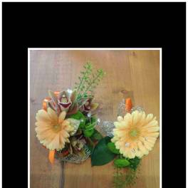 Two floral corsages with pale yellow blooms and orange ribbon accents