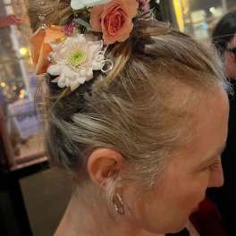 Floral hairpiece with white orchids, peach roses, and white daisies