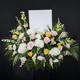 Floral standing spray with pink and yellow roses and white blooms