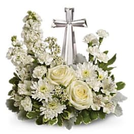 White floral arrangement with roses and daisies around a silver cross