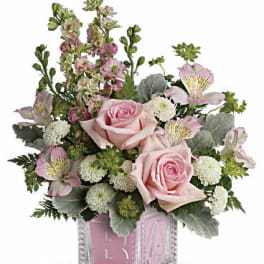 Pink roses and mixed blooms arranged in a clear glass cube vase