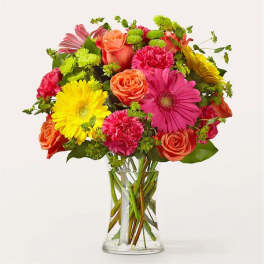 Colorful bouquet of roses, gerbera daisies, and carnations in a clear glass vase