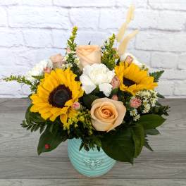 Mixed bouquet with sunflowers, roses, and white blooms in a blue vase