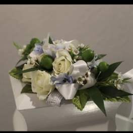 Small arrangement of ivory roses with white and pale blue flowers and ribbon on a white box