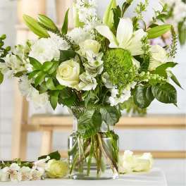 White flowers arranged in a clear glass vase with green accents