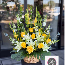 Yellow roses and white lilies in a wicker basket arrangement