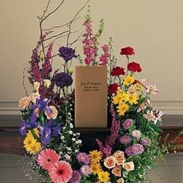 Large floral wreath with mixed colorful flowers around a central sign