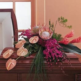 Tropical floral arrangement with pink anthuriums and protea on a wooden casket